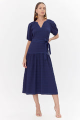 Model wears midi, navy dress with a tie belt and drop waistline.