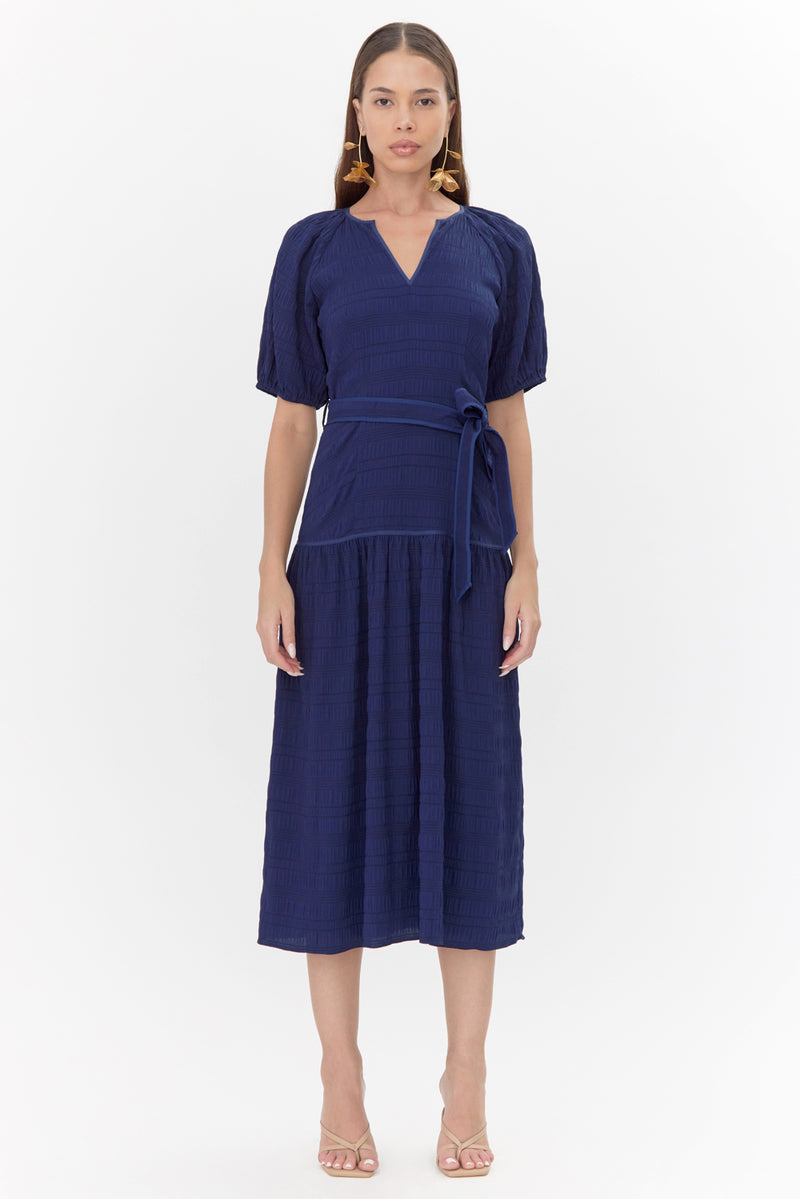 Model wears midi, navy dress with a tie belt and drop waistline.