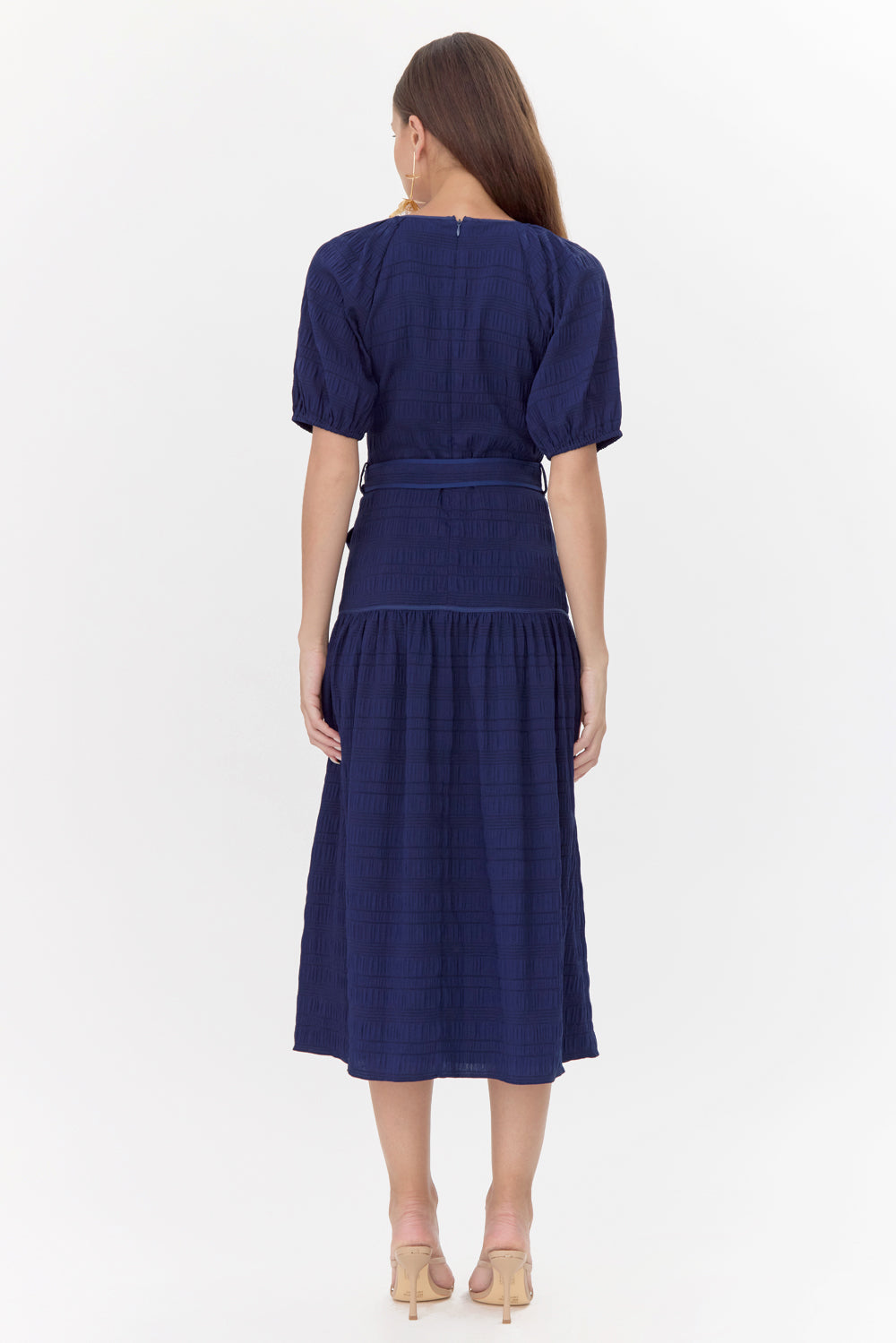 Back of model wearing midi, navy dress with a tie belt and drop waistline.