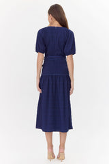 Back of model wearing midi, navy dress with a tie belt and drop waistline.