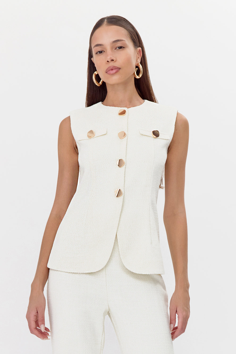 Model wearing a feminine tweed vest featuring gold, rounded square buttons.