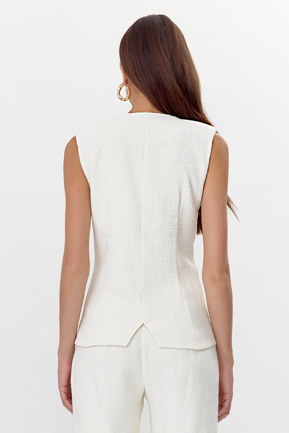 Back view of model wearing a feminine tweed vest featuring gold, rounded square buttons.