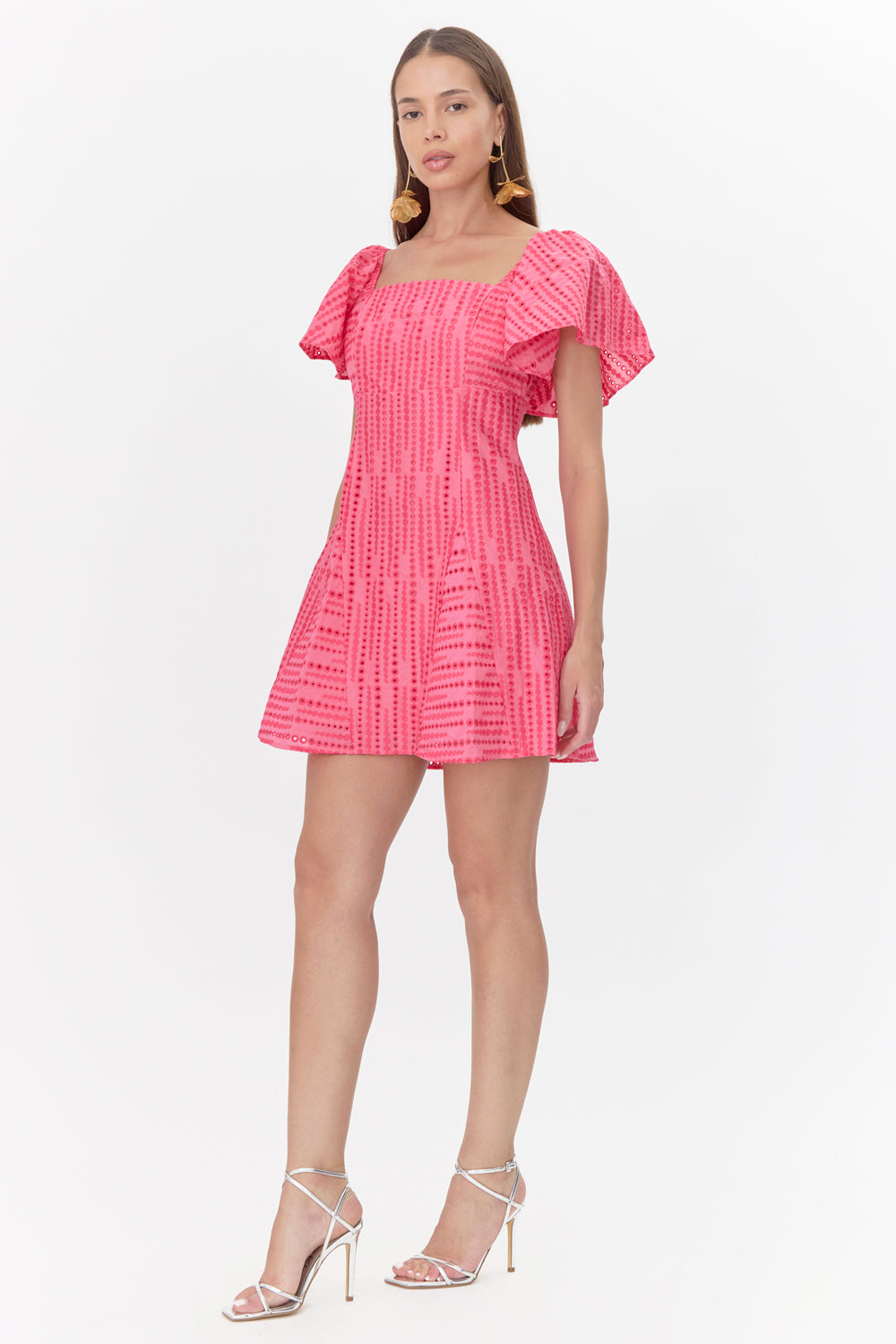 Full body view of model wearing a pink mini dress featuring flutter sleeves and embroidered polka dots.