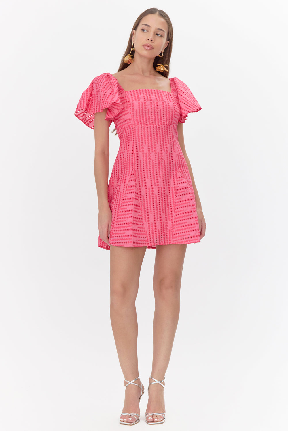 Full body view of model wearing a pink mini dress featuring flutter sleeves and embroidered polka dots.